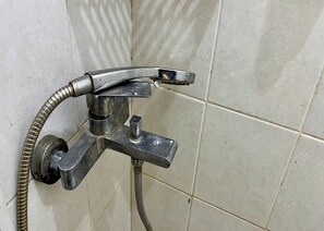 A metallic shower faucet with a flexible hose, mounted on a tiled wall. - Rb Residence Grogol (Jakarta)