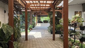 A covered walkway with hexagonal tiles, wooden beams, and potted plants. - Annet Homestay (Sleman)