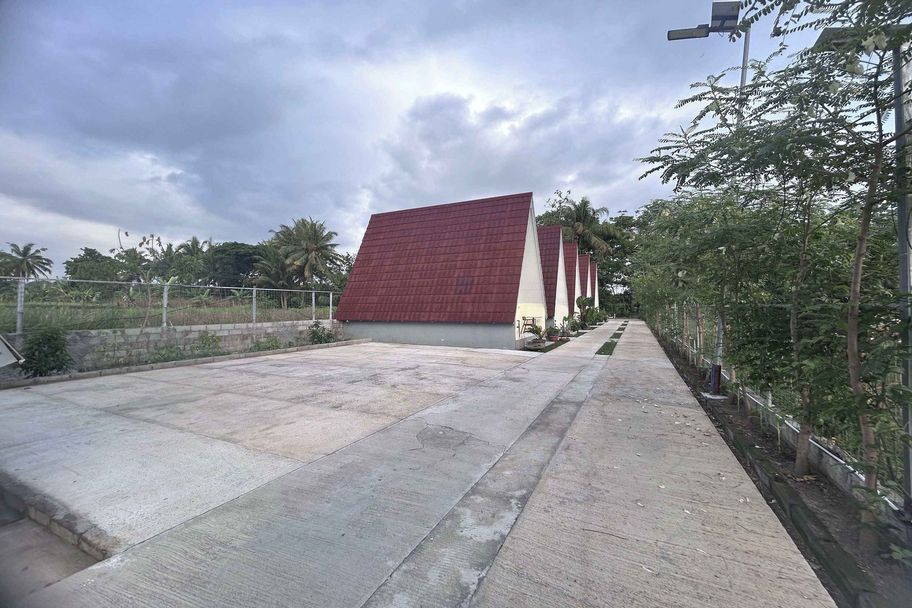 Un bâtiment avec un toit rouge et un chemin en béton qui y mène.