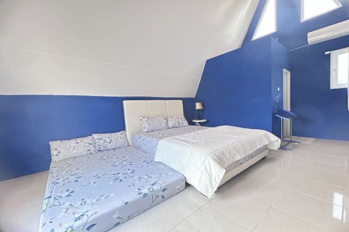 A bedroom with a large bed, a nightstand, and a window.