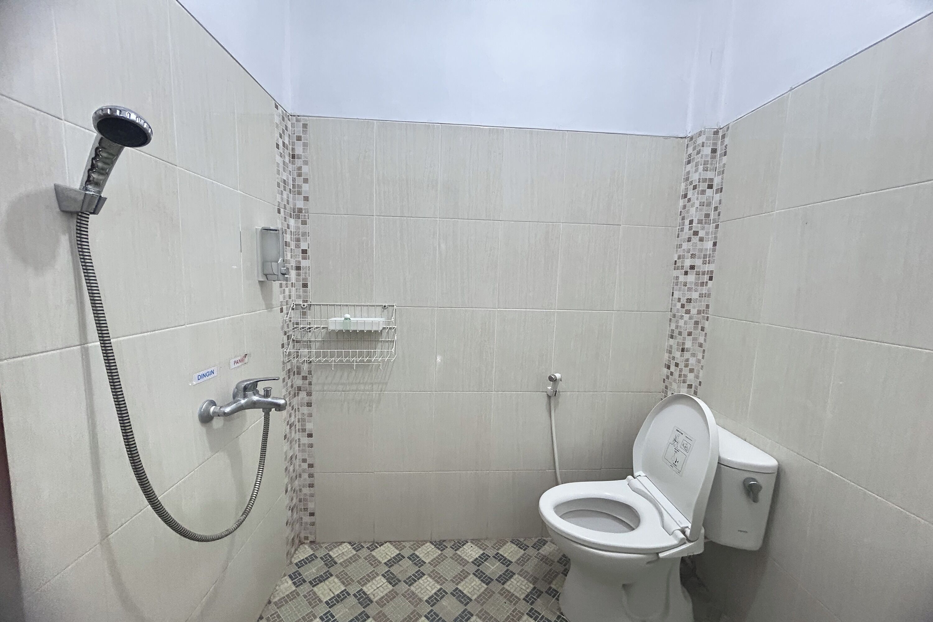A small, tiled bathroom with a shower, toilet, and a wall-mounted soap dish.