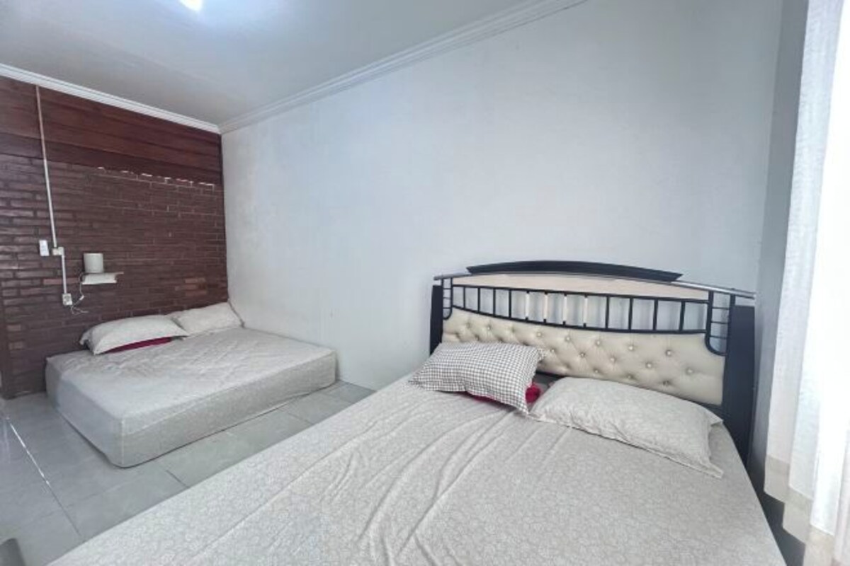 A bedroom with a bed, a bench, and a brick wall.