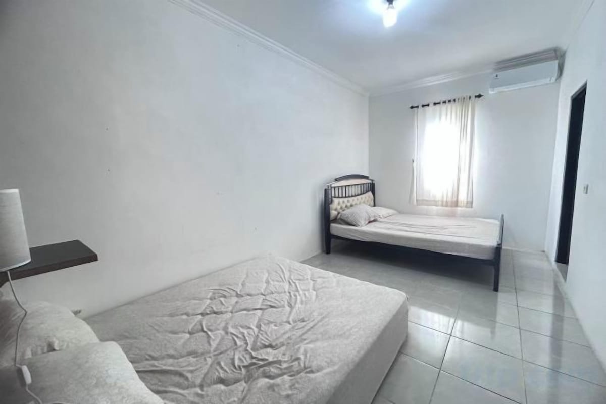 Un dormitorio con una cama individual, una mesita de noche y una ventana con cortinas.