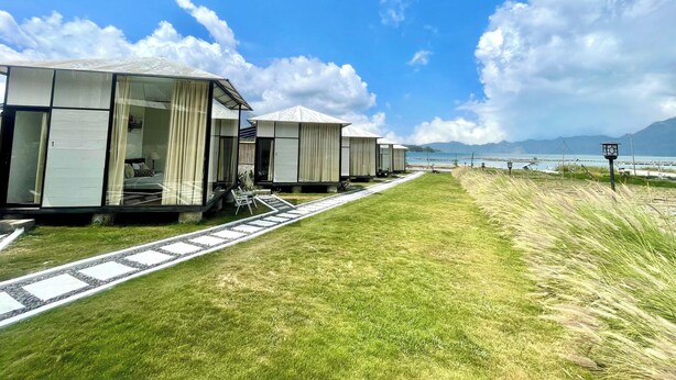 A row of modern, glass-walled cabins with a pathway leading to a beach. - Double U Camp And Villa (Kintamani)