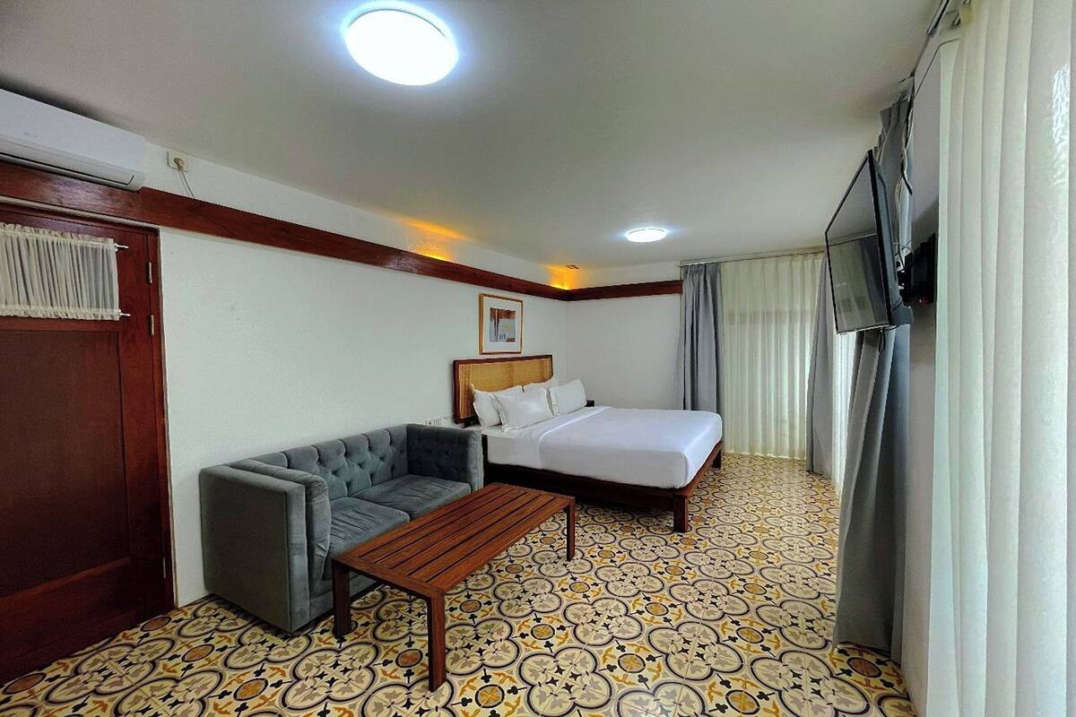Een hotelkamer met een bed, een slaapbank, een houten tafel en een vloer met patroon.