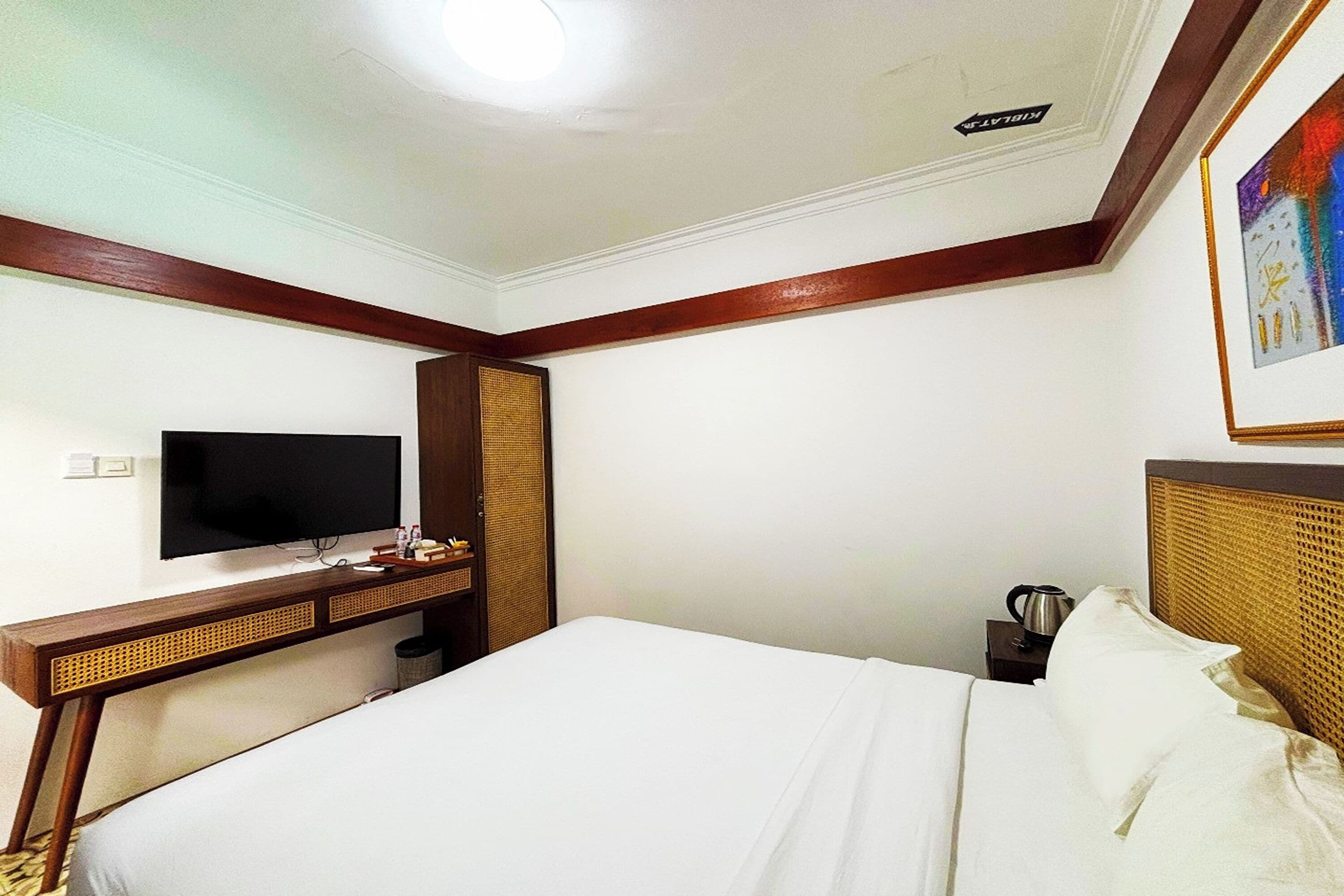 A hotel room with a bed, a television, a desk, and a coffee maker.