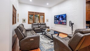 Ein modernes Wohnzimmer mit Ledersofas, einem Glastisch und einem flachbildfernseher an der Wand.