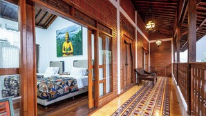 Ein Hotelzimmer mit einem Bett, einem Sessel, einem großen Buddha-Gemälde und einem Teppichläufer mit Muster.