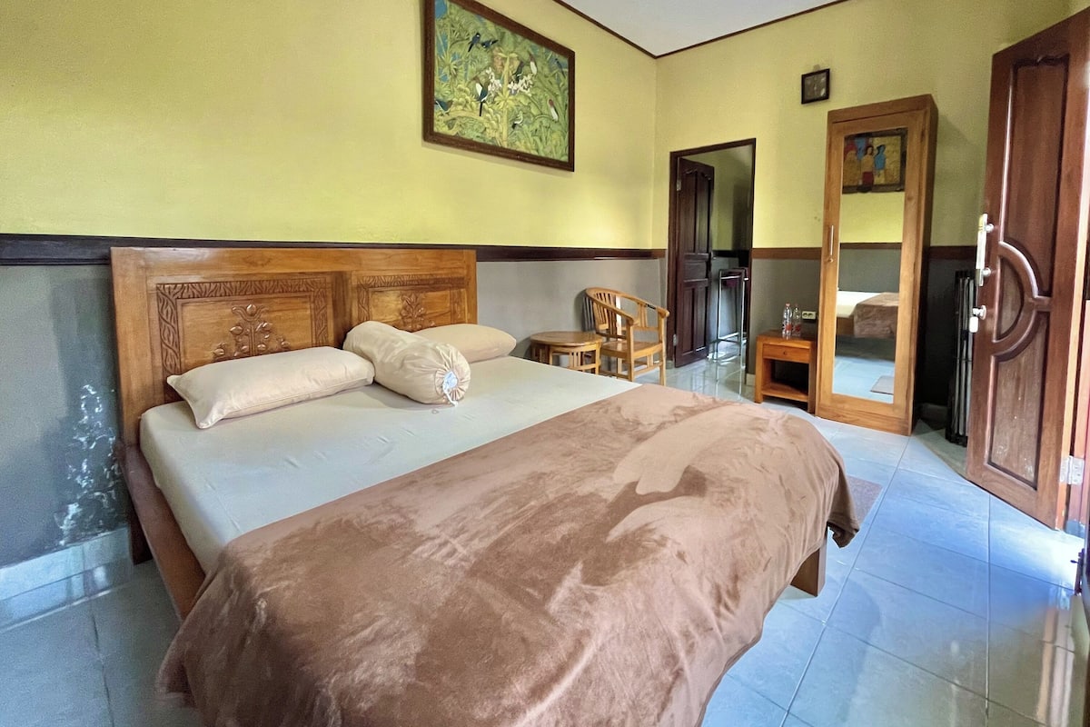 Une chambre à coucher avec un grand lit, une tête de lit en bois, une chaise, une petite table et une armoire.