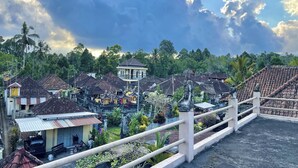 A traditional village with thatched-roof houses, a central temple, and a bridge. - Mongan Homestay Beside The Belulang Hot Spring (Penebel)