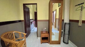 A hallway with a wooden chair, a small wooden table with bottles, and a mirror on the wall. - Mongan Homestay Beside The Belulang Hot Spring (Penebel)