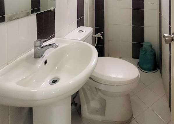 Ein Badezimmer mit einem weißen Waschbecken, einer Toilette und einem grünen Mopp.
