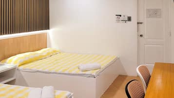 Una camera da letto piccola e ordinata, con un letto, un comodino, una sedia e una porta con un cartello.