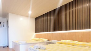 Habitación de hotel con dos camas, cabecero de madera y diseño moderno.