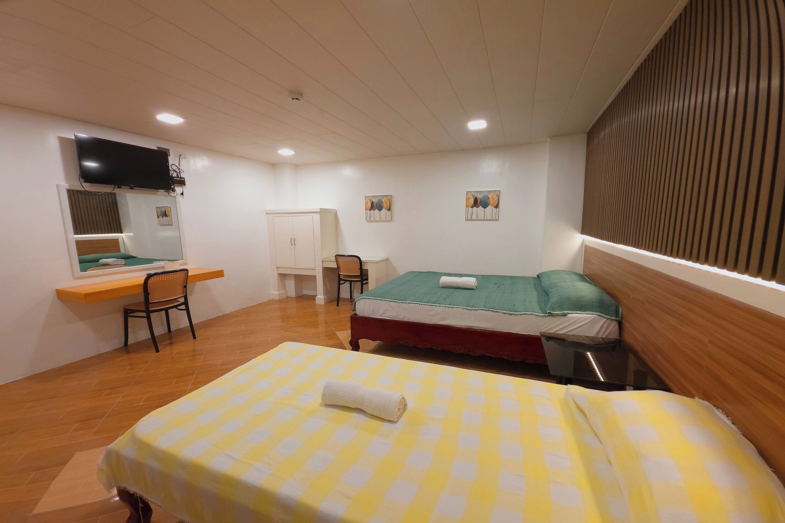 Una habitación con cama, escritorio, silla y televisor.