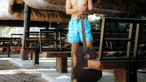A person standing under a thatched roof structure, holding a guitar. - Ilocos Urban Wave Resort Hotel (Laoag)