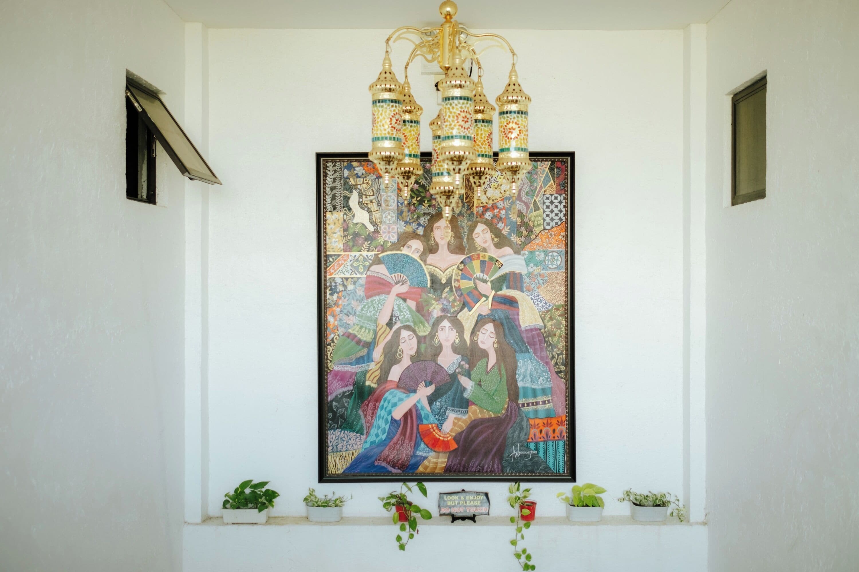 A wall-mounted artwork with a chandelier above it.