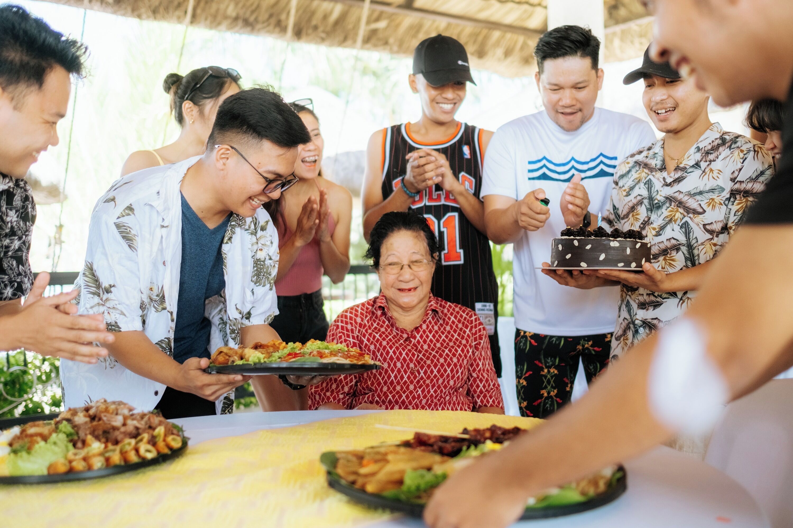 Un grupo de personas reunidas alrededor de una mesa con diferentes platos, sugiriendo una comida compartida o celebración.