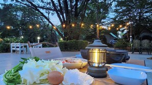 Une table dressée à l’extérieur, avec une assiette de nourriture, une lanterne et un bol.