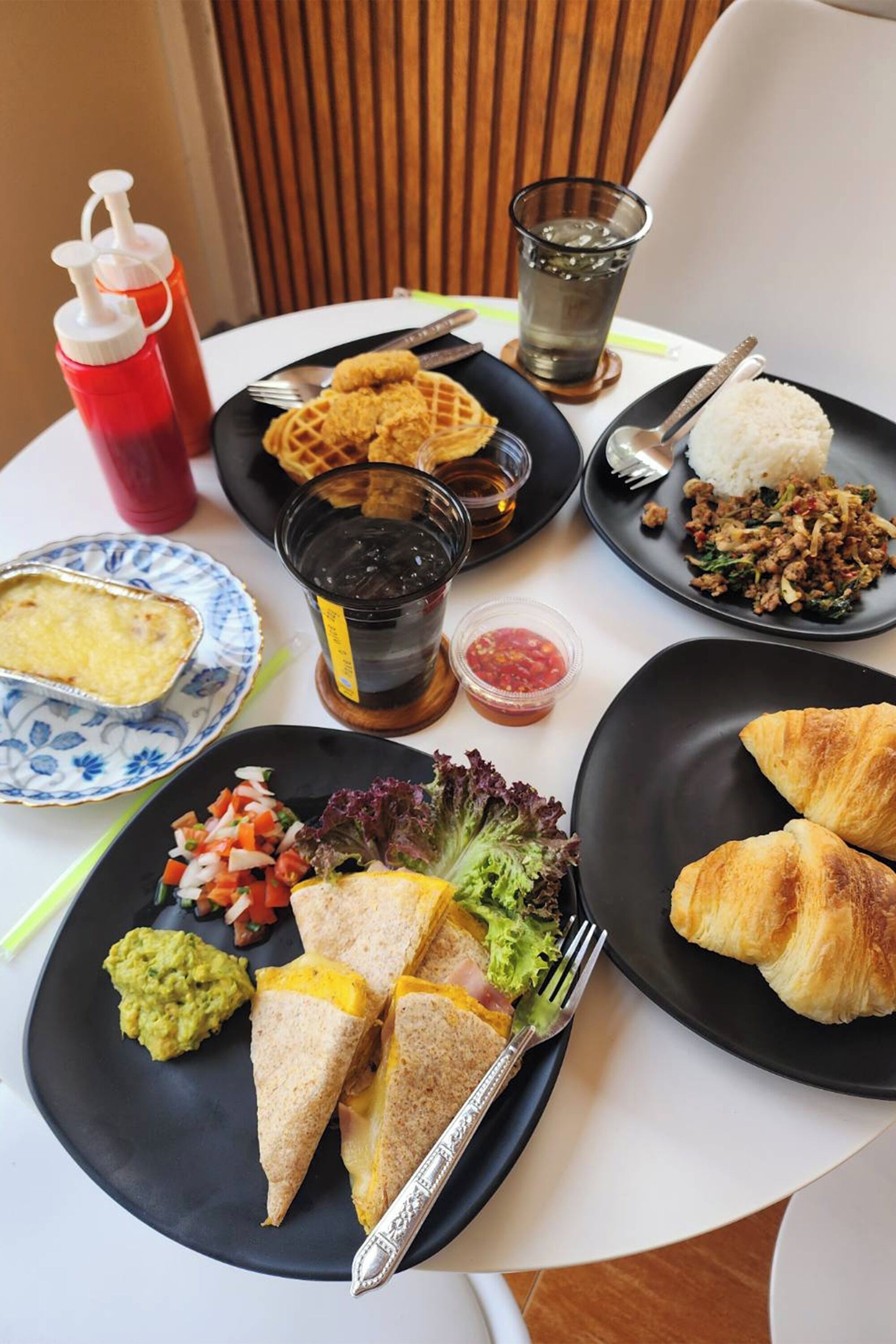 Een tafel met diverse gerechten, waaronder wafels, rijst en sandwiches.