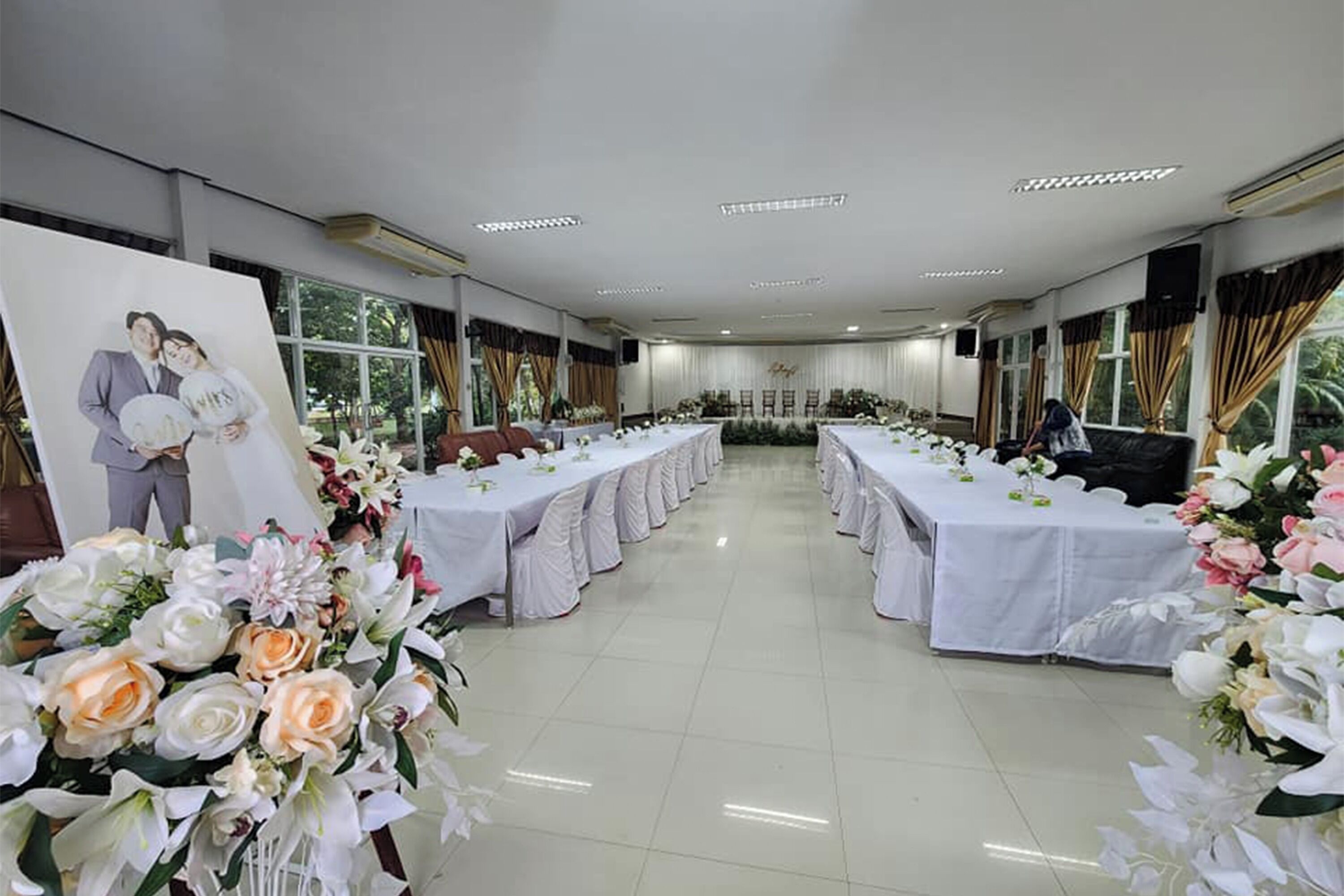 Un salón de banquetes con mesas largas, manteles blancos y arreglos florales.