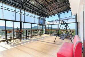 A spacious balcony with a view of mountains, metal railings, and a red chair. - Ruby Hotel Phu Quoc (Phu Quoc)
