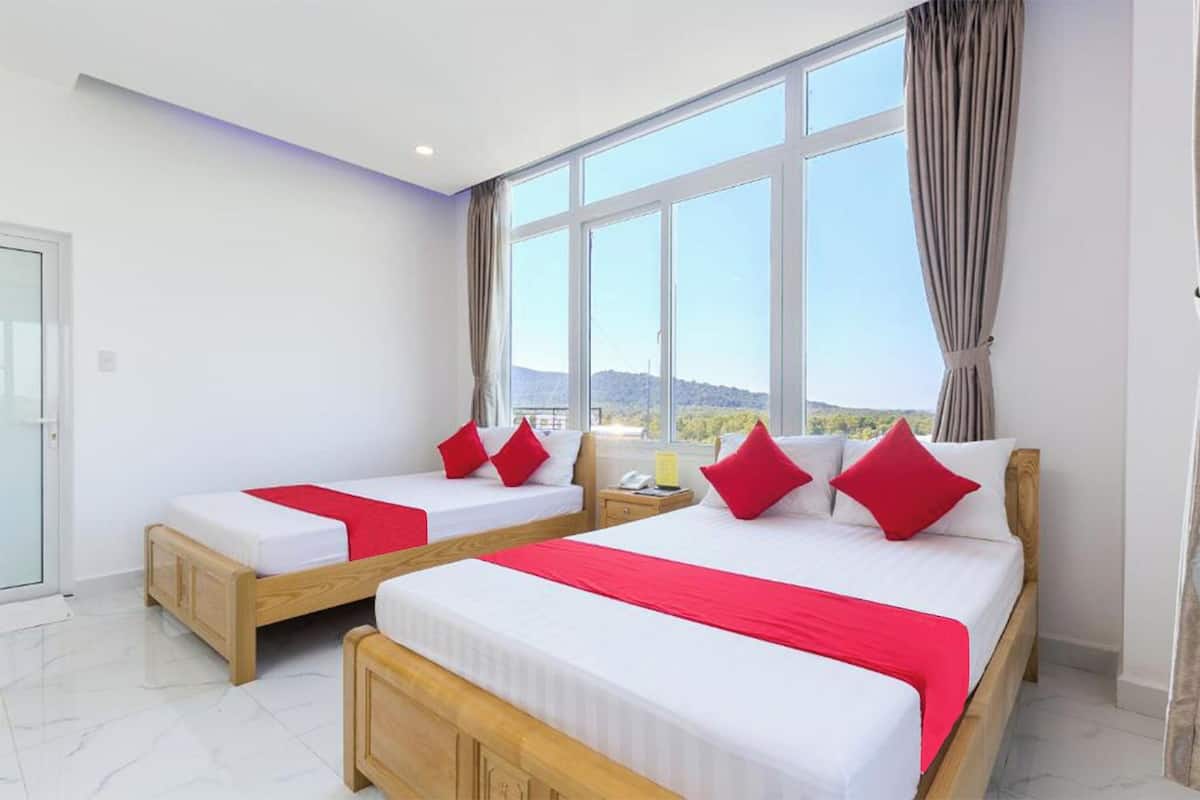 A hotel room with two beds, a large window, and a view of the landscape.