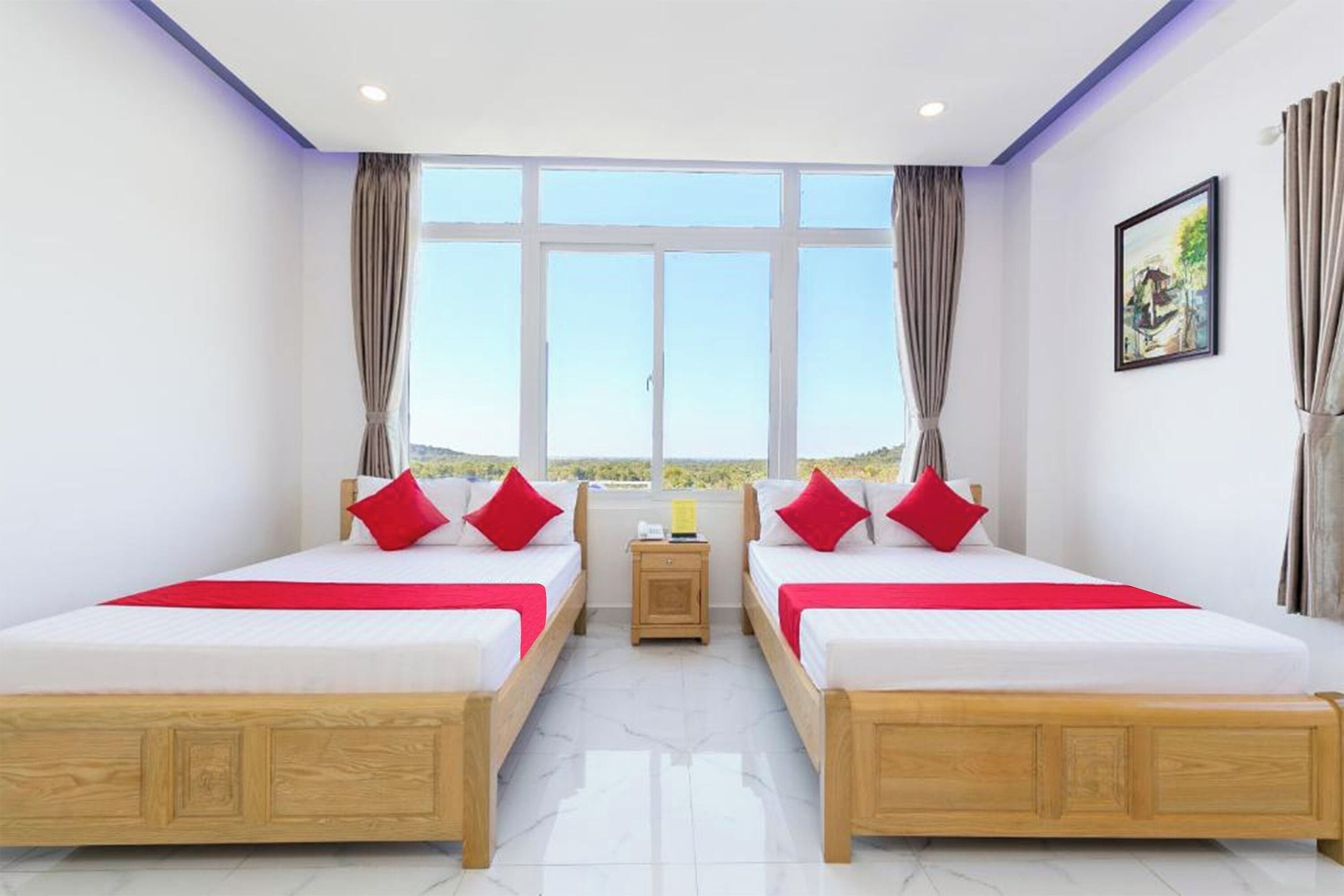 A hotel room with two beds, a nightstand, and a window with curtains.