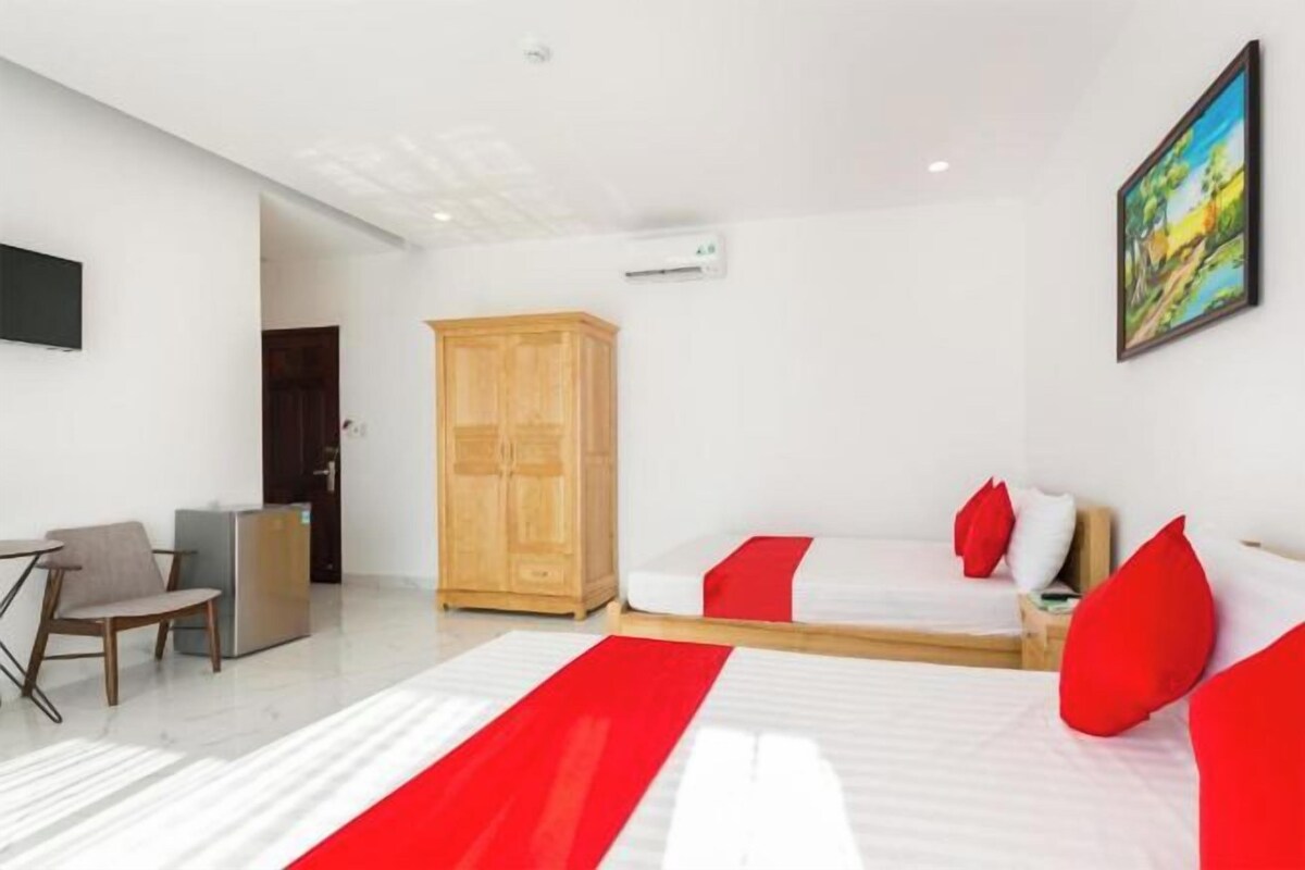 A hotel room with a bed, a desk, a chair, a wardrobe, and a painting on the wall.