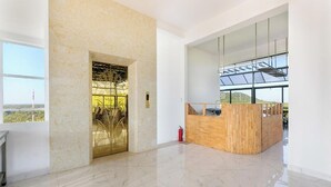 Un hall d’entrée spacieux, doté d’un sol en marbre, d’un comptoir de réception et d’une grande fenêtre donnant sur l’extérieur.