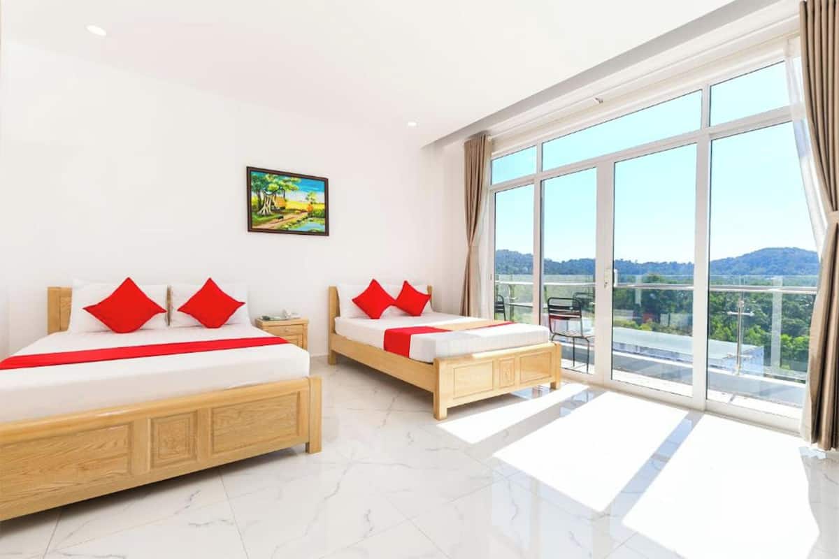 A hotel room with two beds, a large window with a view, and a painting on the wall.