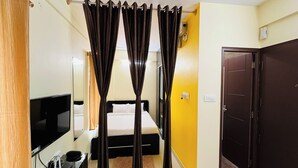 A hotel room with a bed, a TV, a desk with a computer, and a wardrobe. - Marvel Comforts Near Fortis Hospital, Bannerghatta Road (Bengaluru)