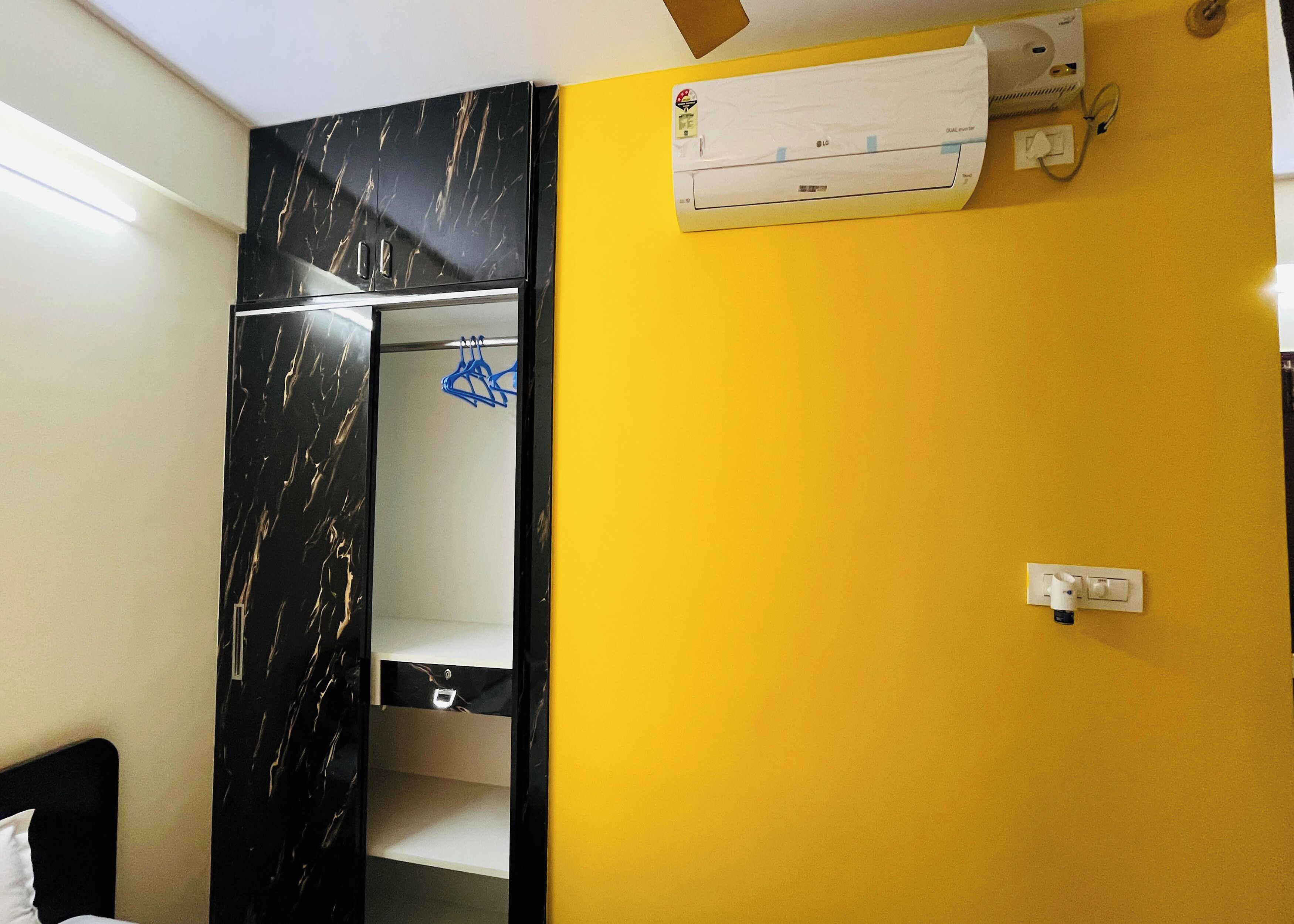 A room with a black marble wardrobe, a yellow wall, and an air conditioning unit.