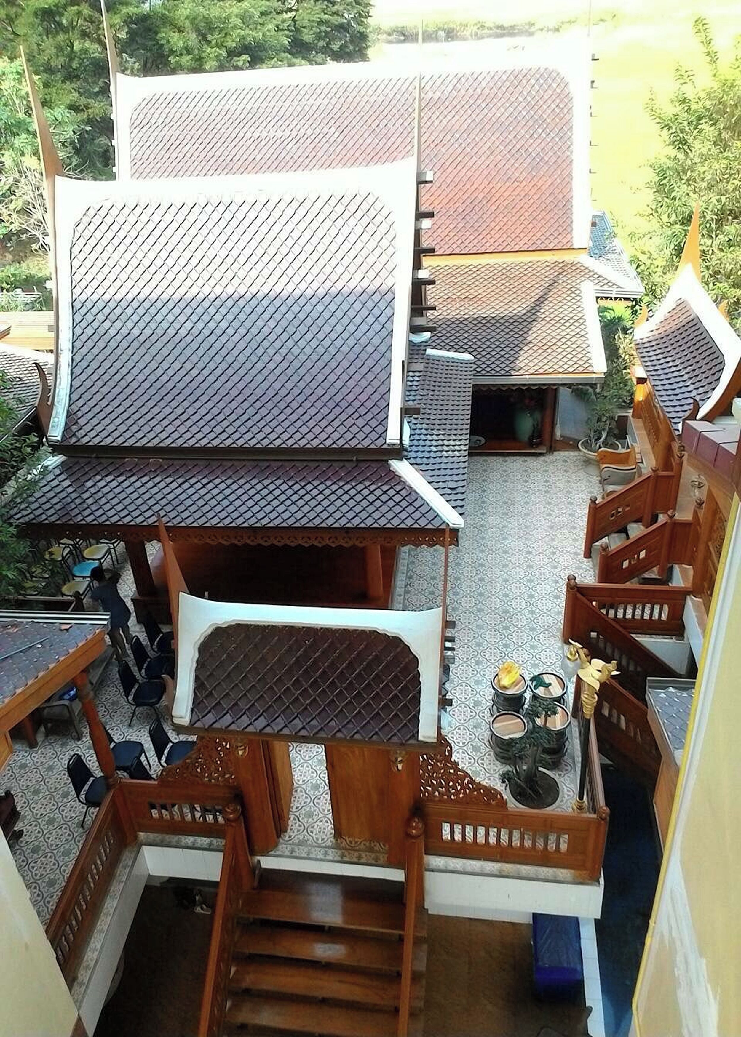 A traditional Thai house with a tiled roof, wooden staircase, and a small garden area.