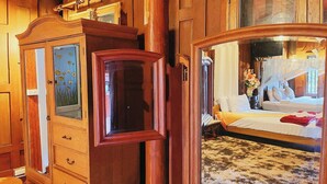 Un mobile in legno con ante in vetro, un letto con copripiumino bianco e uno specchio che riflette la stanza.