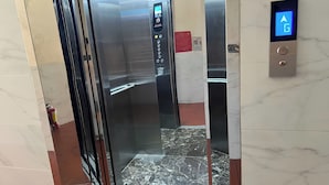An elevator interior with a digital control panel, marble flooring, and a fire extinguisher near the door. - Thanh Hang Hotel (Ho Chi Minh City)