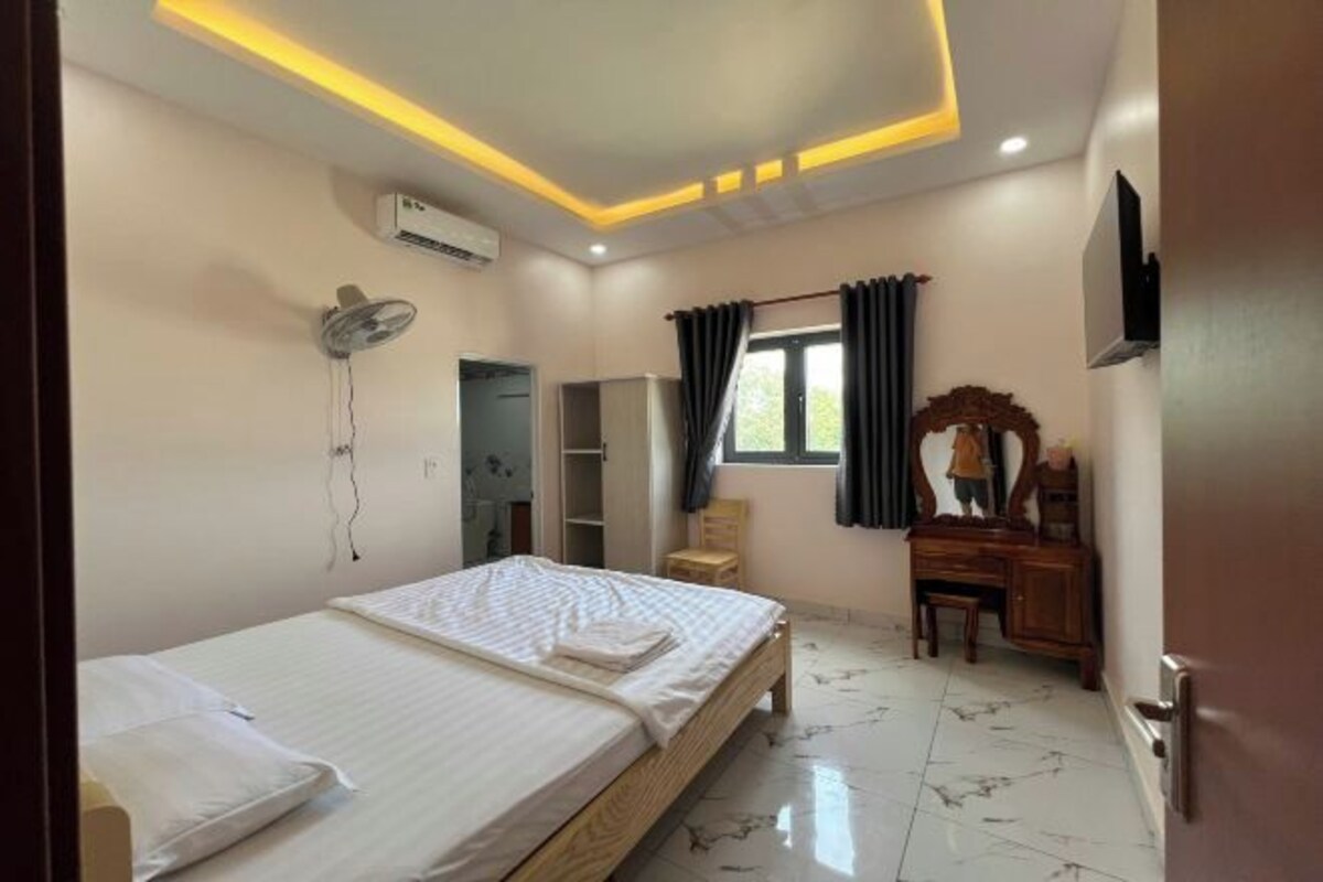 Une chambre à coucher comprenant un lit, un bureau, une chaise, une armoire et un ventilateur de plafond.