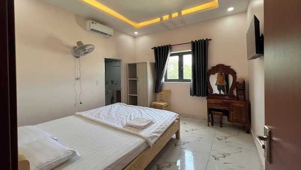 A hotel room with a bed, bedside table, wardrobe, vanity with mirror, and a TV mounted on the wall. - Thanh Hang Hotel (Ho Chi Minh City)
