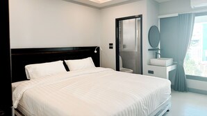 A modern hotel room with a large bed, a bedside table, a mirror, and a window with curtains. - Smith Hotel (Chiang Mai)