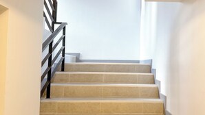 A staircase with beige tiles and black railings. - Smith Hotel (Chiang Mai)