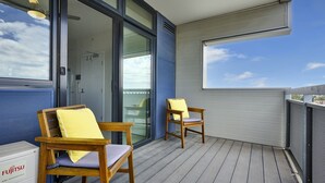 A balcony with two wooden chairs and a table, a glass door leading to an interior space, and a view of the sky. - Coburg Loft – 270° Views Skyline Escape (Coburg)