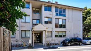A multi-story building with a central entrance, a covered porch, and a parking area with two cars. - The Nest Elwood - Beachside Escape with Free Parking (Elwood)
