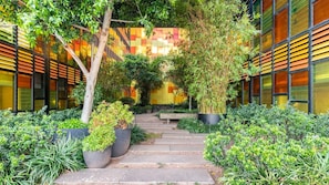 Stunning building with a geometric facade, surrounded by a lush garden and steps leading to a cozy bench.