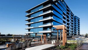 A modern multi-story building with balconies and a rooftop patio area. - The Atrium - Resort-Style Glen Waverley Stay with Parking (Glen Waverley)