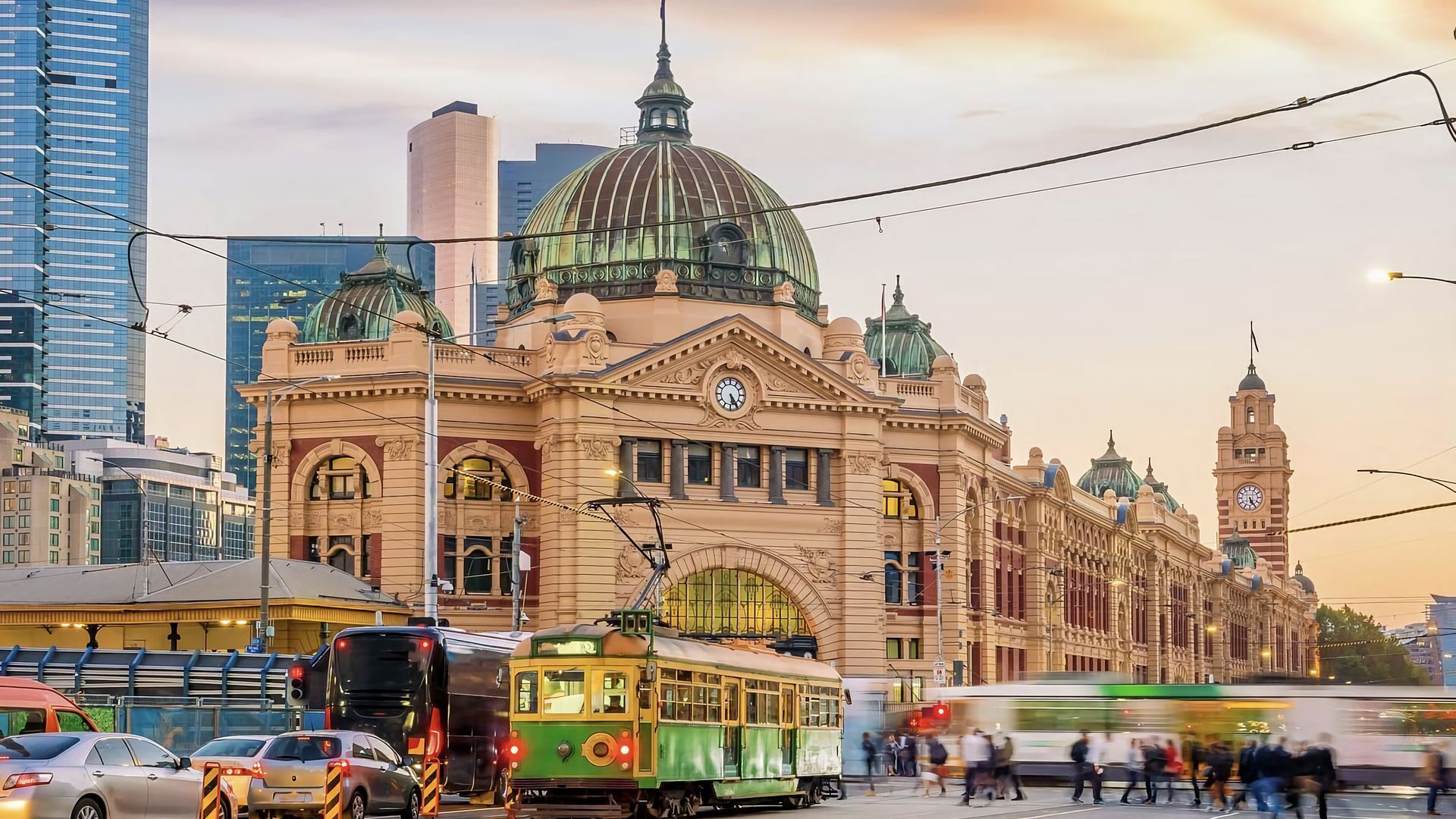 A historic building with a large dome and clock tower, surrounded by modern buildings and busy street traffic.