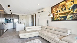 Una sala moderna con un sofá modular, una cocina y una mesa de comedor.