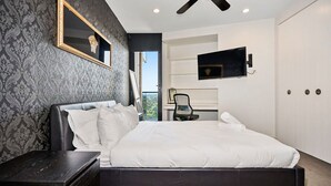 Un dormitorio moderno con una cama grande, un escritorio y una televisión montada en la pared.