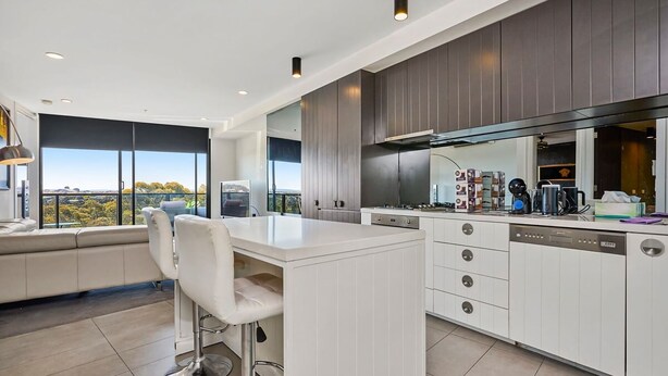 Una cocina moderna con una isla grande, electrodomésticos integrados y vistas al exterior.