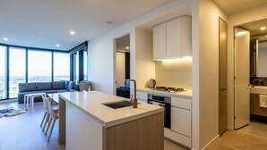 A modern kitchen with a central island, built-in appliances, and a large window offering a city view.