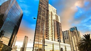 Un immeuble de grande hauteur doté d’une façade moderne en verre, entouré d’autres bâtiments imposants.